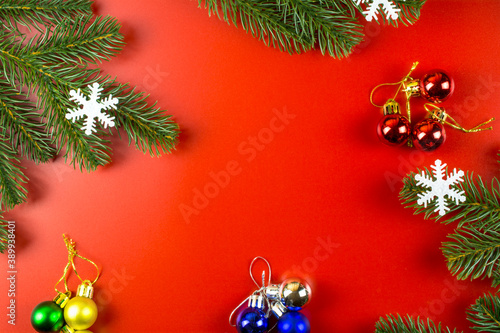 Christmas decorations  snowflakes and fir branches on a red background with space for text.