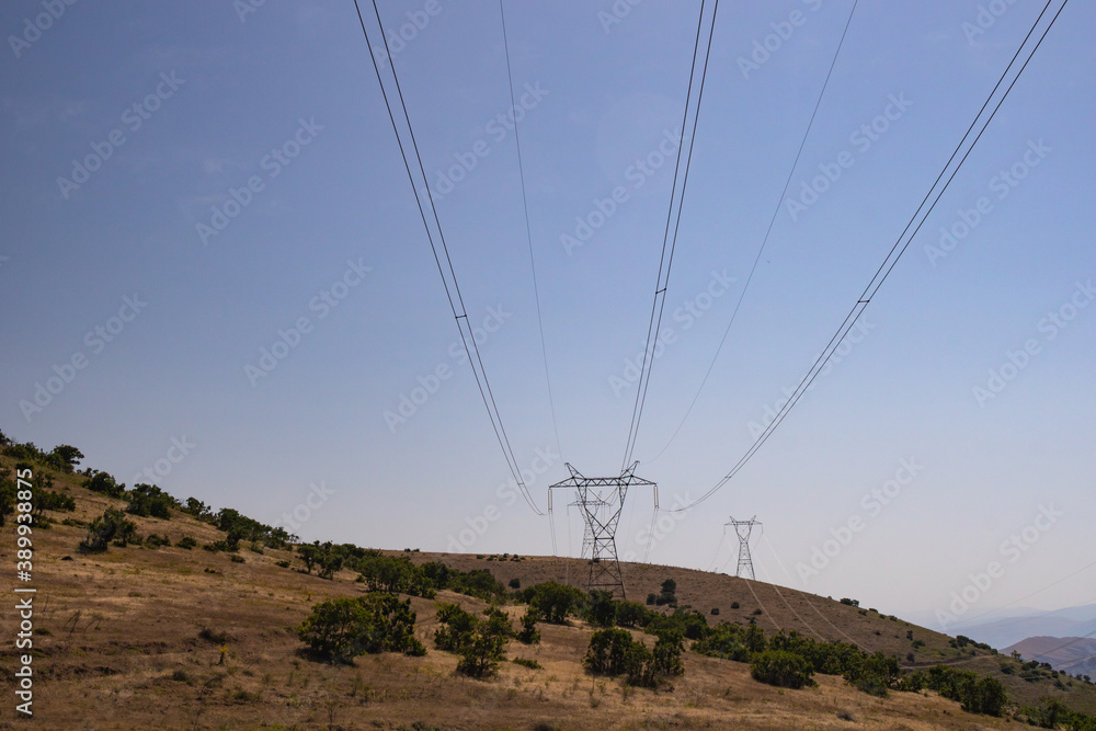 High voltage electricity lines on the hills. Electricity transmission on the steppe. 