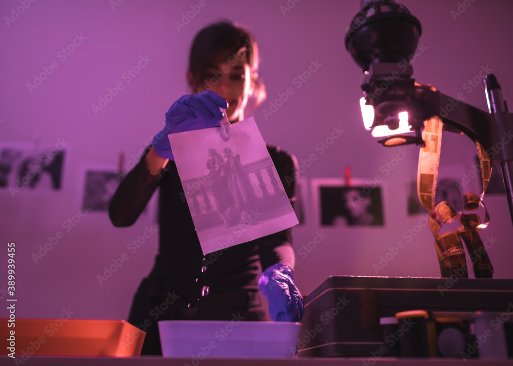 Female photographer developing film and printing photographs in