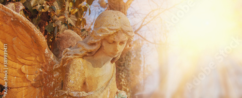 Guardian angel. Ancient stone statue in sunlight. Copy space for design.