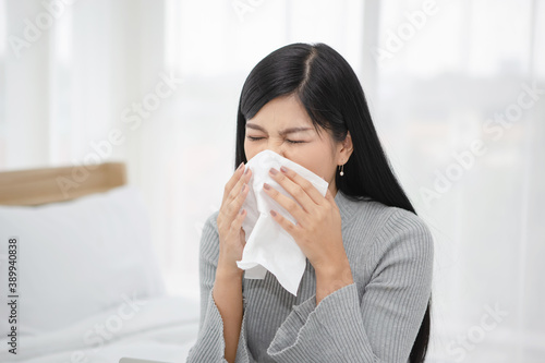 Young woman got nose allergy and sneezing in a tissue paper in the bedroom 