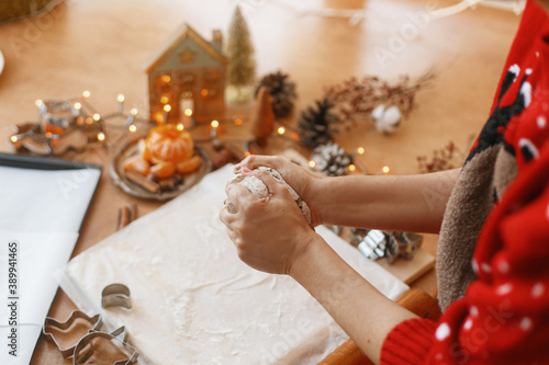 Hands kneading raw gingerbread dough on background of metal cutters on rustic table. Christmas