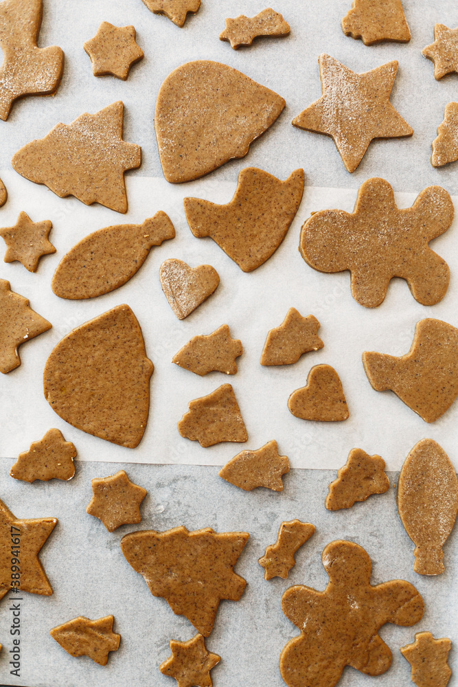 Cooking gingerbread cookies. Raw gingerbread cookies in festive christmas shapes on oven tray Cooking gingerbread cookies. Raw gingerbread cookies in festive christmas shapes on oven tray