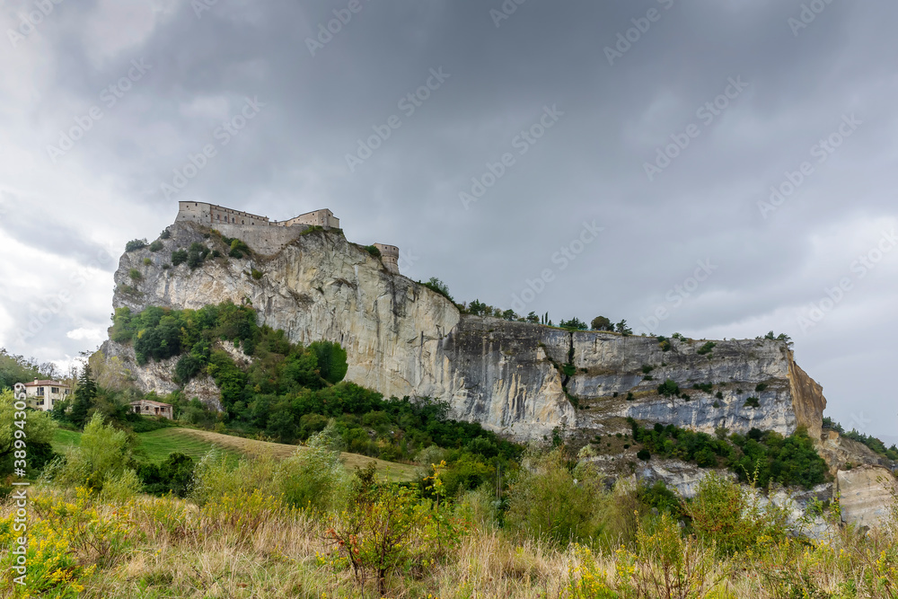 The imposing fortress of San Leo, Emilia Romagna, Italy, under a stormy sky with rain clouds