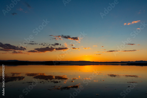 Sunset over the lake and hills. Partly clouds on the sky. reflection of the clouds on the lake. 