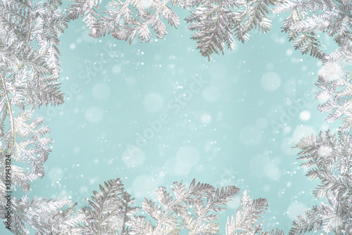 Winter and Christmas Festive Snowy Background with Silver Xmas Decor Branches, over light blue background. Christmas and New Year greeting card concept, copy space