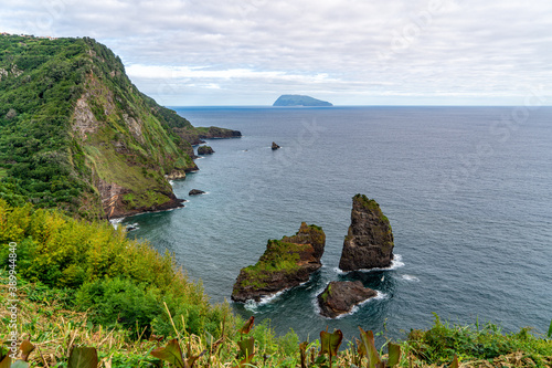 Azores, Flores island, view from the Miradouro dos Caimbros of the rocks in the Baia de Alagoa and the island of Corvo in the background. photo