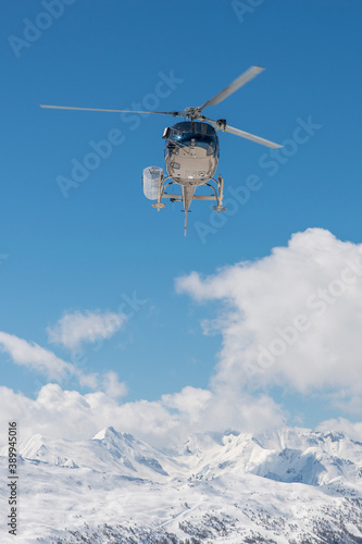 Helicopter on the sky in French French alps in winter, snowy mountains in France