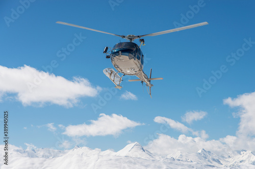 Fototapeta Naklejka Na Ścianę i Meble -  Helicopter on the sky in French French alps in winter, snowy mountains in France