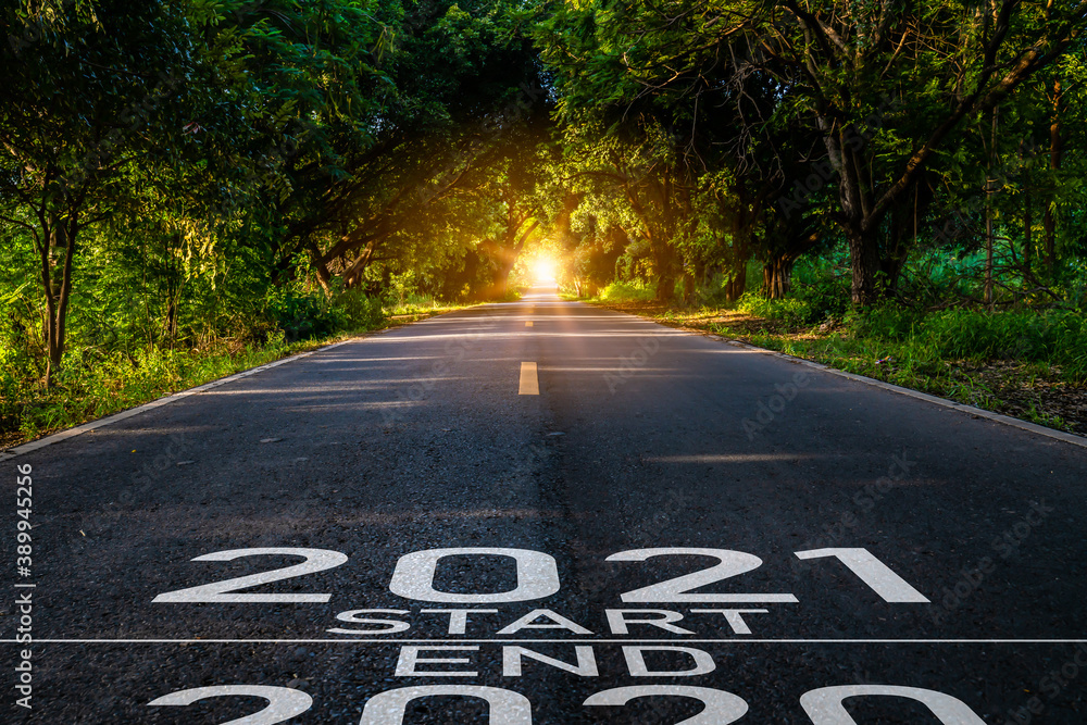 Obraz premium New year 2021 or start straight concept.word 2021 written on the road in the middle of asphalt road at sunset.Concept of planning and challenge or career path,business strategy,opportunity and change
