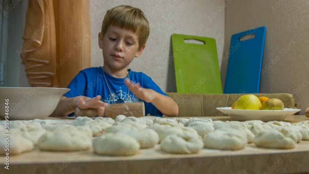 A boy is cooking meat pies in the kitchen A boy is cooking meat pies in the kitchen