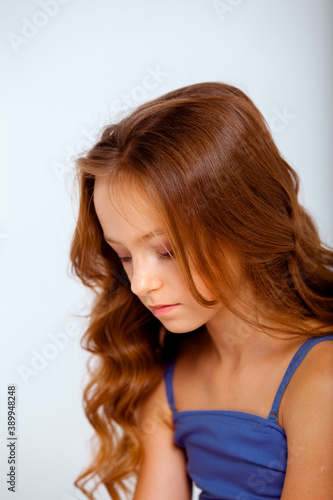 dressed in a light blue dress on spaghetti straps cute little girl on a white background