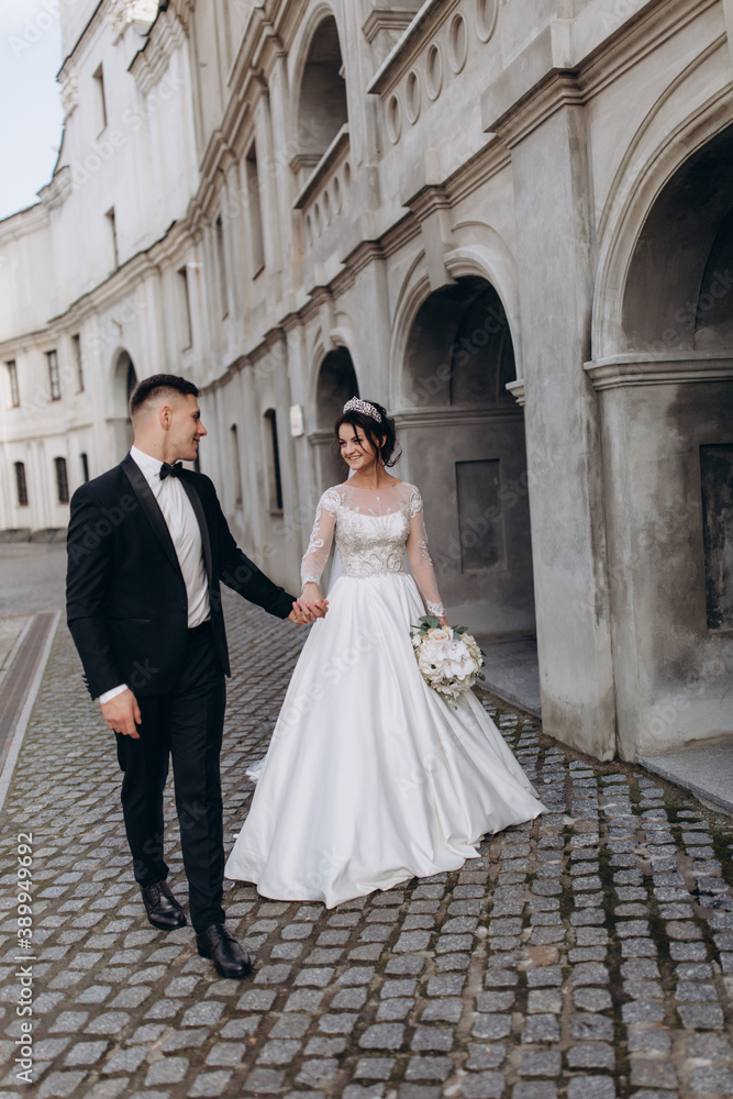 Romantic walk of the groom and the bride through the streets of the city. Photo session with the cathedral in the background.