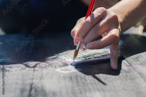 Close up of a womans hand holding a brush painting a wooden table