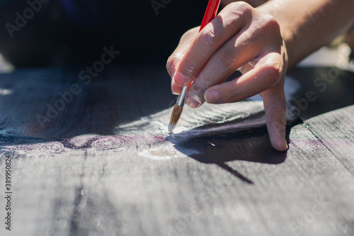 Close up of a womans hand holding a brush painting a wooden table