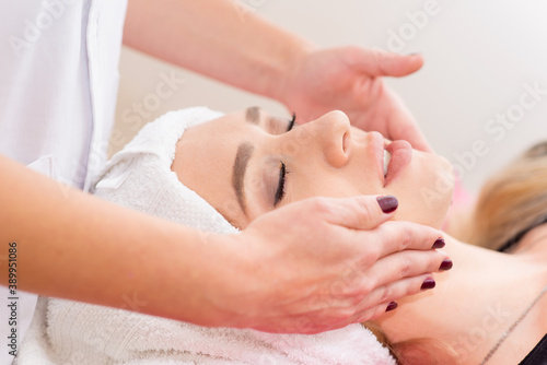 beautician doing facial massage to woman in clinic