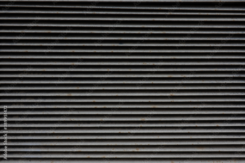 Gray metal louver grille. There are dirt and rust spots on the metal strips. Background. Texture. Gray metal louver grille. There are dirt and rust spots on the metal strips. Background. Texture.