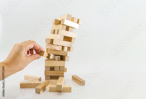 Fotografie Tower of wooden blocks and human hands take one block