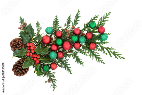 Christmas decoration with holly, cedar cypress, pine cones & red & green baubles on white background. Decorative element for the festive season. Flat lay, top view, copy space.