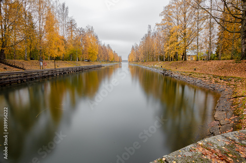 View of the Vääksu canal, in autumn, yellow birches on the bank and reflection in the water. It's a nasty day .