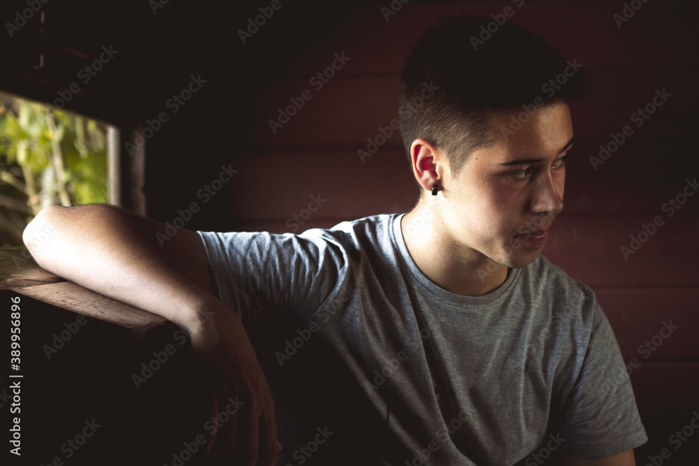 Young adult looking through the window of a wooden cabin.