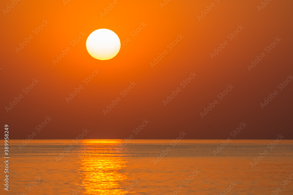 warm orange sun on the horizon from the sea during sunrise