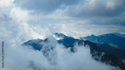 High altitude photo with the steep peaks of Fagaras Mountains rising through dense clouds and fog.