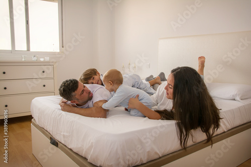 Portrait Of Happy Family Wearing Pajamas In Bed. Family Playing In Bed With Her Children. Family Lifestyle.