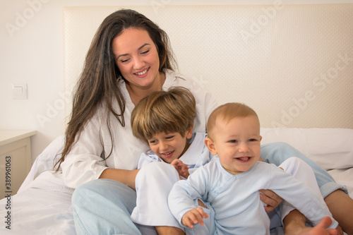 Mom And Children Playing. A Mother And Her Children Play In Bed. Family Lifestyle.