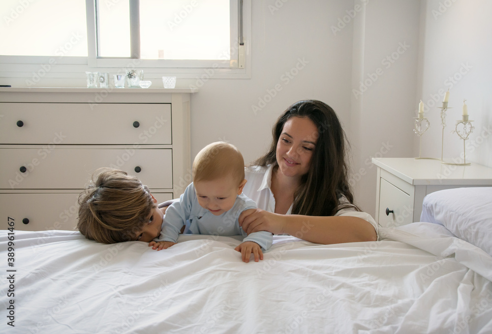 Mother And Children In Bed Looking At Camera For A Photo. Family Lifestyle