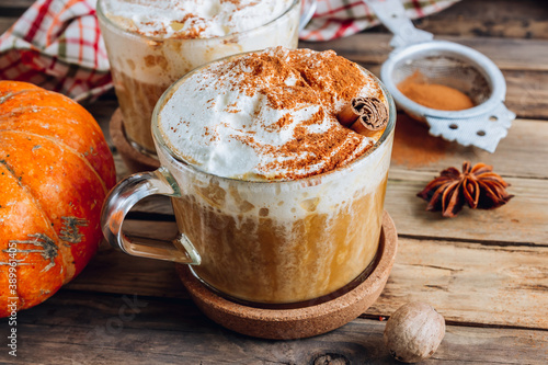 Pumpkin spiced latte or coffee in a glass on a vintage table. Autumn or winter hot drink.