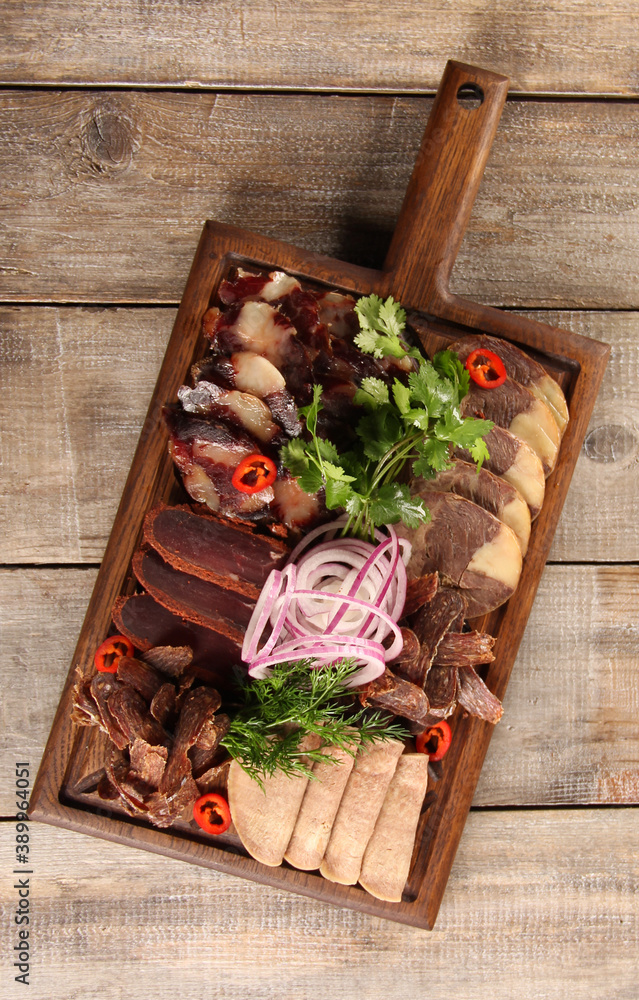 Oriental cuisine. Meat snack. Kazy. Homemade boiled horsemeat sausage with spices and fresh herbs. Beef tongue with onion and chili pepper. Rustic. Background image, copy space. Top view, flatlay