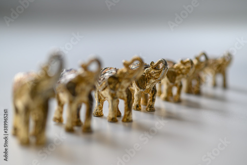 Photography figures of gilded elephants stand in a row in height