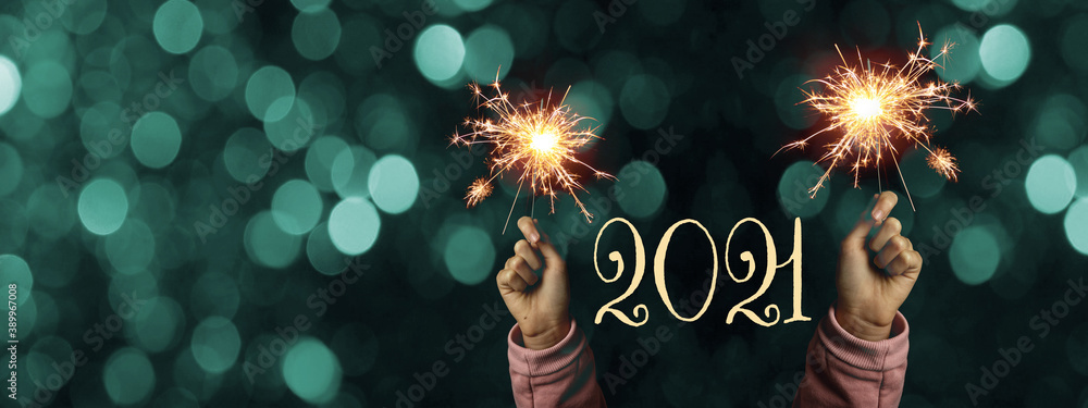 Happy New Year 2021 background banner panorama - Happy girl hold sparkling sparklers in her hands at dark night with turquoise bokeh lights - obrazy, fototapety, plakaty 