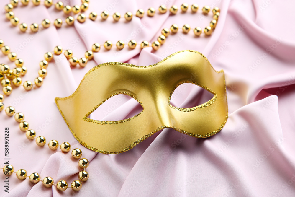 Carnival mask with beads on pink fabric background