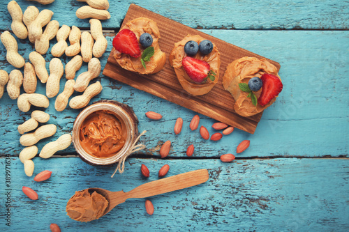 Bread with peanut butter, fruits and nuts on blue wooden table