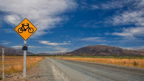Alps to Ocean mountain bike route with a long straight road and a yellow sign with a bike symbol