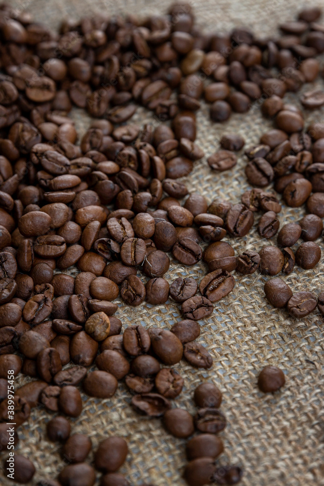 Scattered roasted coffee beans on burlap. Close-up. Vertical. Scattered roasted coffee beans on burlap. Close-up. Vertical.