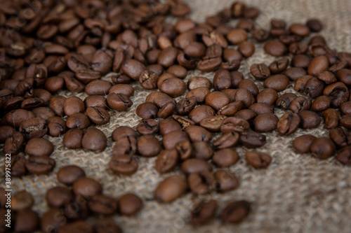 Scattered roasted coffee beans on burlap. Close-up.