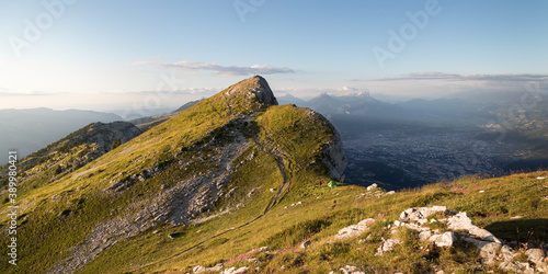 Panorama of a mountain peak with a tent below at sunset