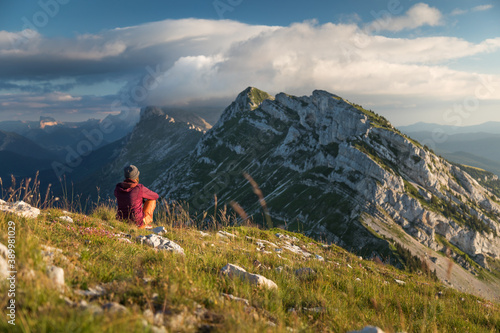 Person sit in the grass watching the mountains under clouds in the Vercors