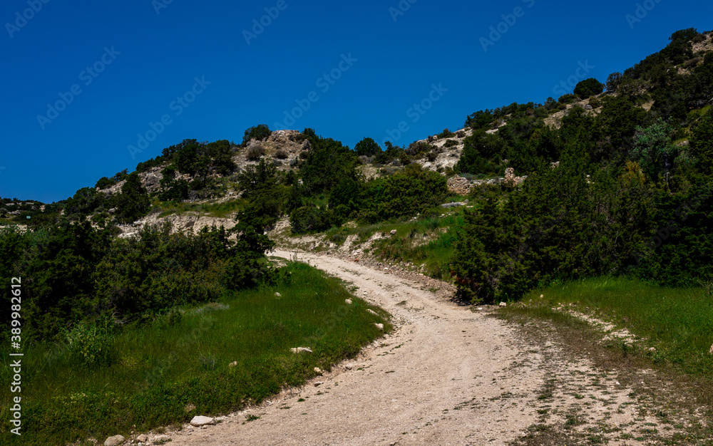 Sandy mountain road of the island of Cyprus in the light of the setting sun. Sandy mountain road of the island of Cyprus in the light of the setting sun.