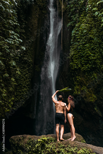 Tourists at the waterfall  rear view. Happy couple at a beautiful waterfall. Couple on vacation in Bali. Honeymoon trip. Vacation on the island of Bali. Tourists in Bali. Copy space