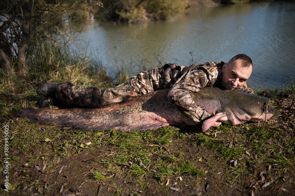 Fisherman holding a giant catfish. Catch of fish, freshwater fishing, monster fish