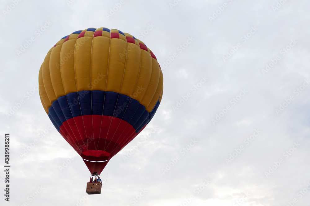 Fototapeta premium Striped yellow blue red balloon against cloudy sky