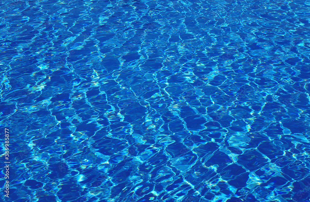 Clear blue pool water with highlights and sun reflections on the surface