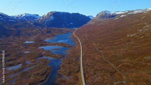 Mountain pass road cutting through rugged terrain and lakes in the highlands in autumn. Aerial video. photo