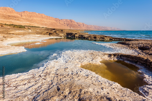 Small multi-colored salt lakes on the shores of the Dead Sea, the lowest point of the Earth on land, near Ein Gedi. The shores of the lakes are covered with white salt. Israel. 