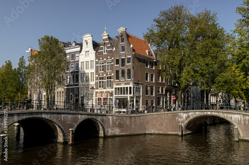 AMSTERDAM, NETHERLANDS - Sep 22, 2020: Amsterdam canal bridges and mansions with trees in autumn sunset photo