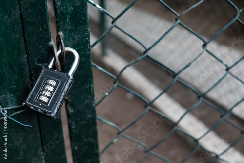 Closed entrance with code padlock on a metal wire fence. Private restricted area with prohibited access. Protected place on lockdown during coronavirus outbreak. Prison or jail concept, classified.